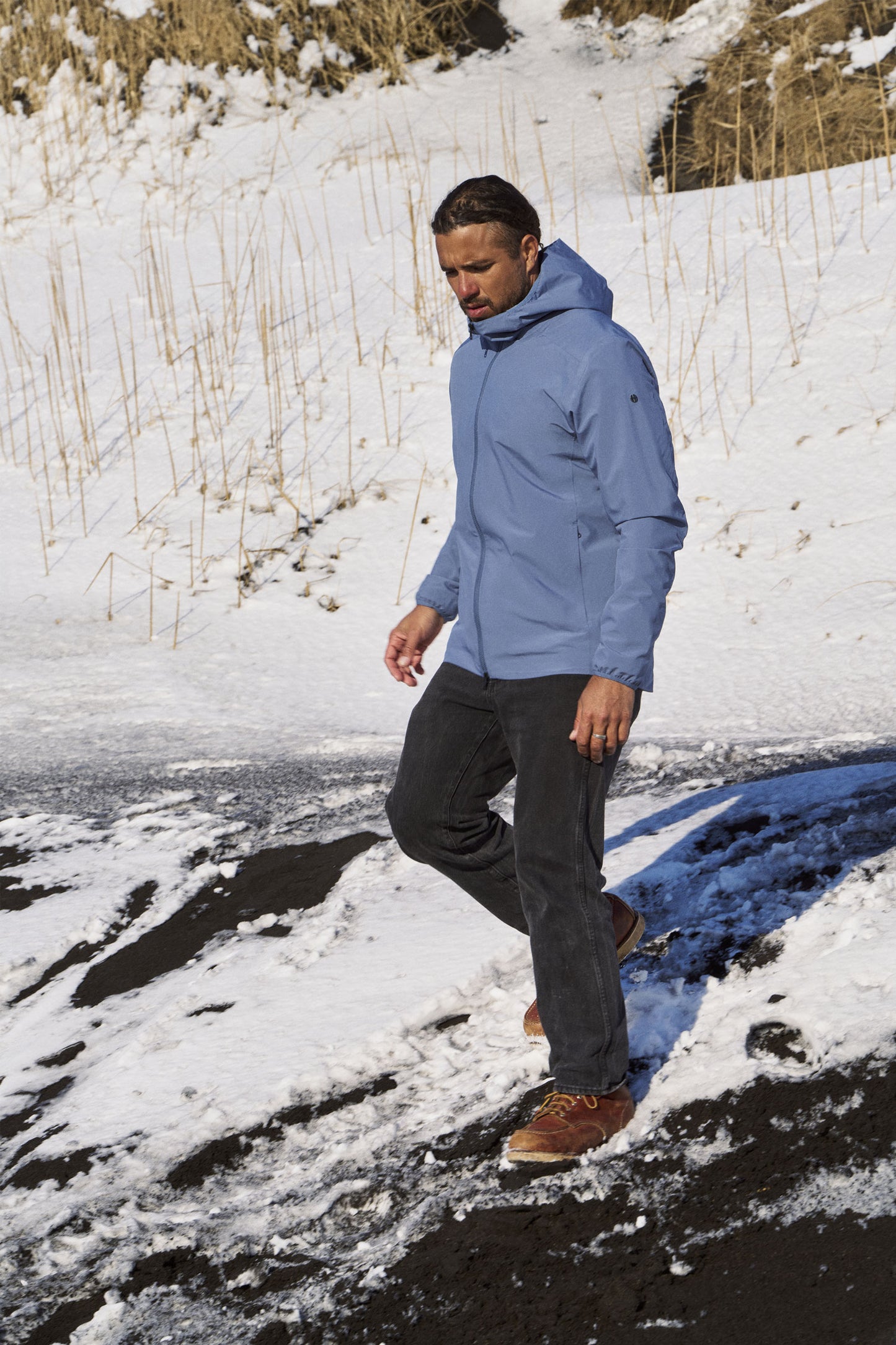 Man in a blue jacket walking on a snowy landscape
