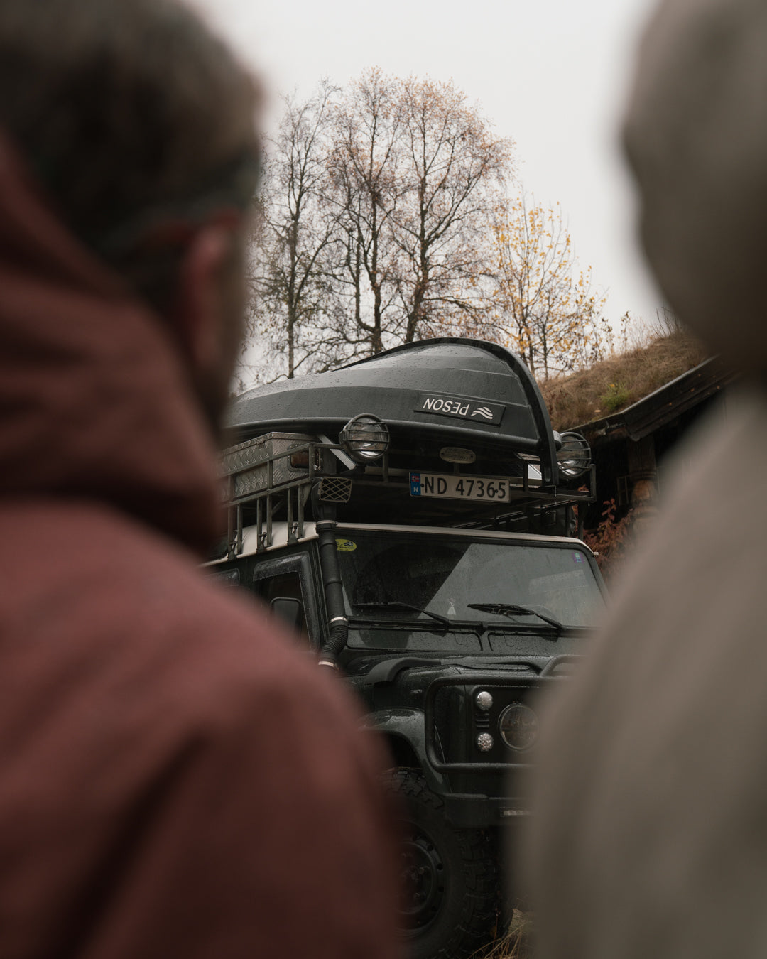 The boat strapped to the roof of the Defender, seen between two people's shoulders
